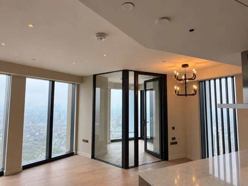 Black candle-style chandelier, recessed LED downlights and brushed wiring accessories in an open-plan luxury apartment with city views, Vauxhall, London