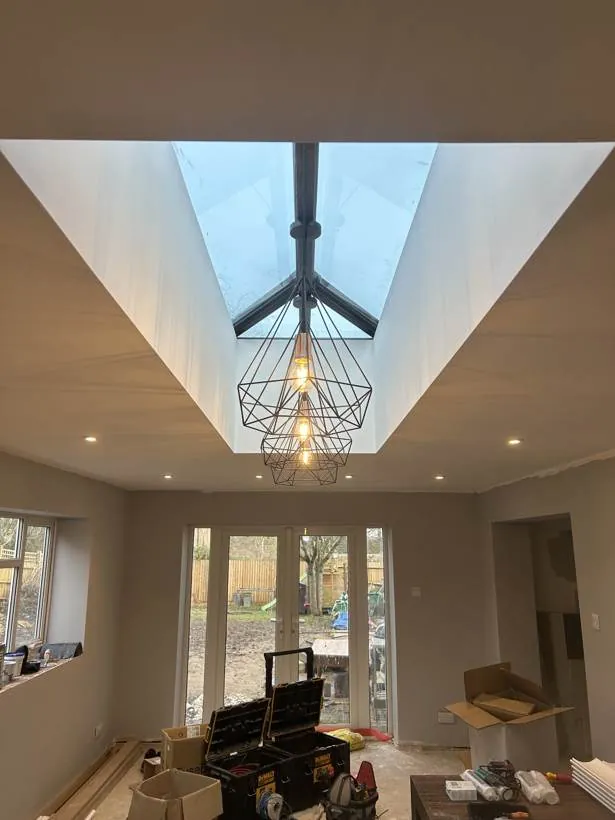 Three geometric wire pendants lit beneath a roof lantern, with downlights around it, during final decoration, Brackley