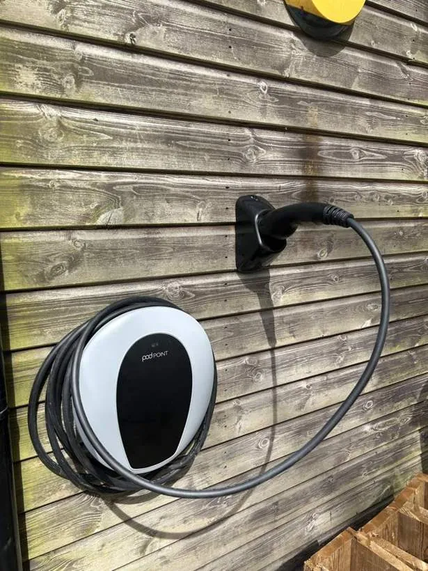 Pod Point home EV charger with tethered cable mounted on timber cladding, village near Bicester