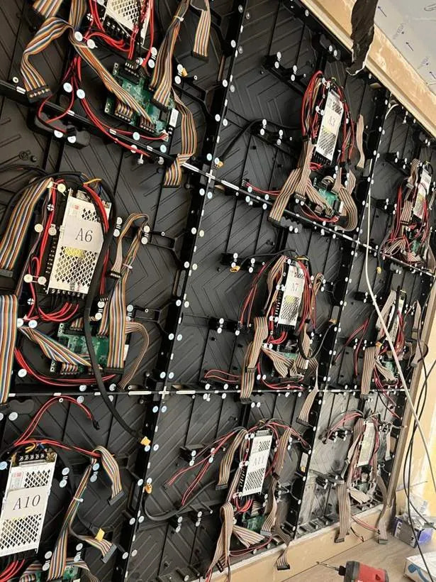 Rear of a large modular LED panel retail screen showing power supplies and neatly routed wiring
