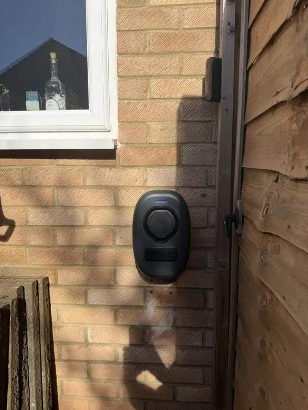 BG Sync EV charger mounted on a brick wall beside a garden gate, Bicester