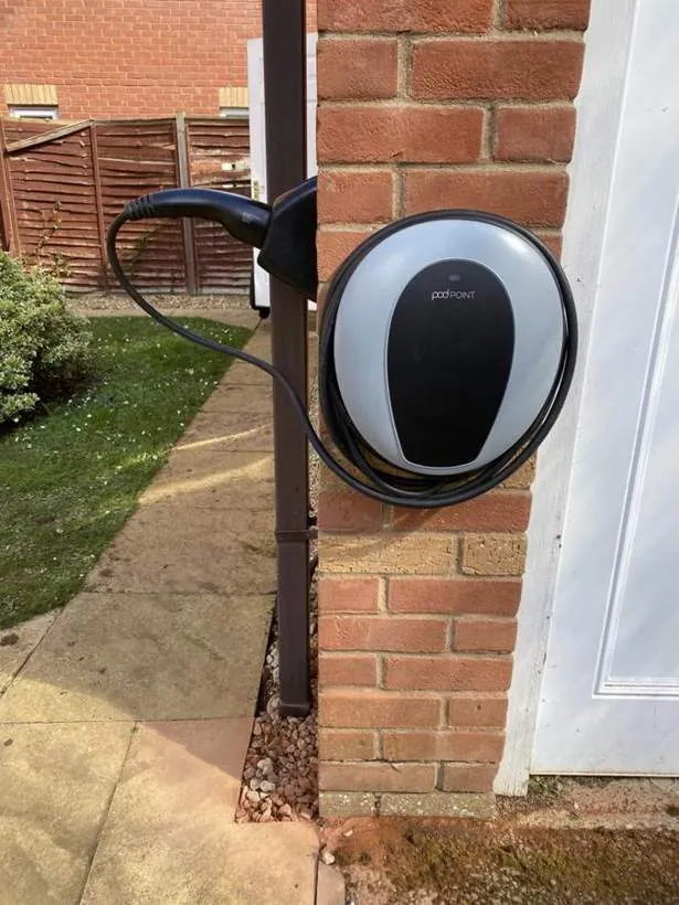 Pod Point EV charger on a brick pier beside a garden path, fed by a long buried cable run, Bicester