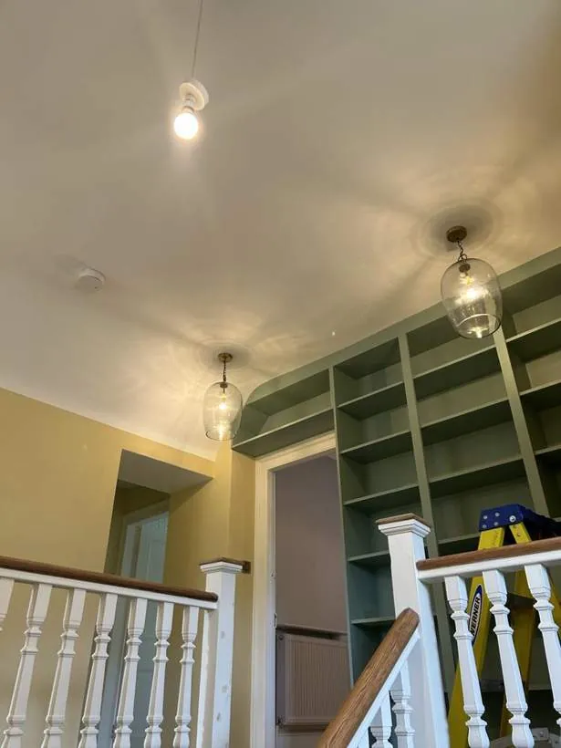Clear glass pendants above a staircase landing with painted bespoke bookshelves