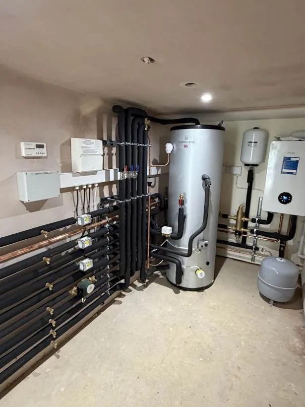 Basement plant room with an unvented hot water cylinder, insulated heating pipework, zone valves and wired controls, Bloxham