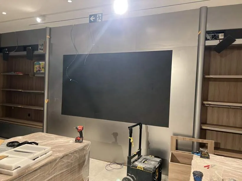 Large black LED panel retail screen mounted between shelving bays during the shop fit-out
