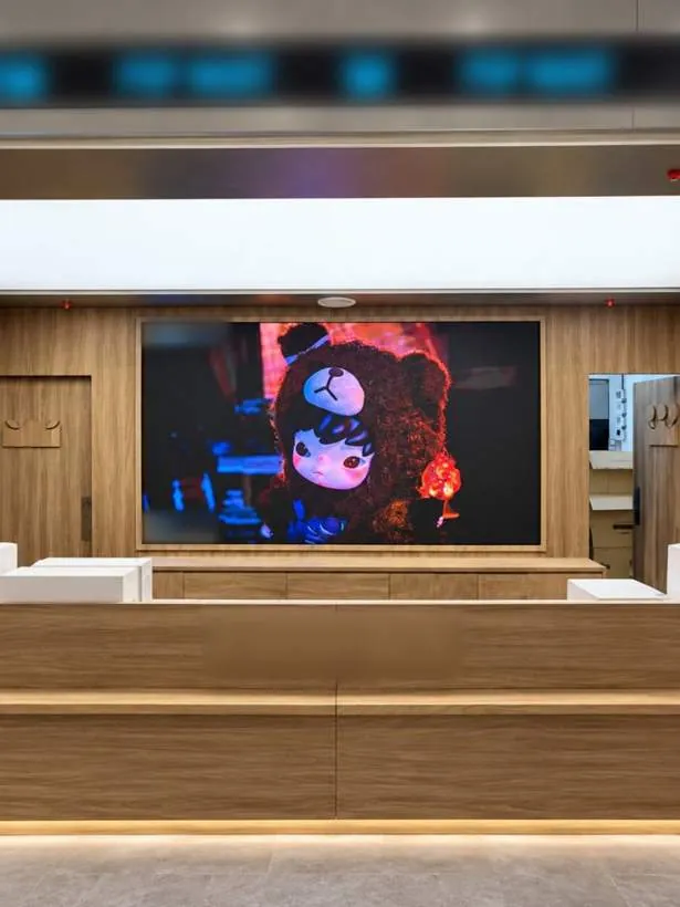 Large LED panel retail screen set into timber panelling behind the till, with LED lighting beneath the counter, completed store in Oxford
