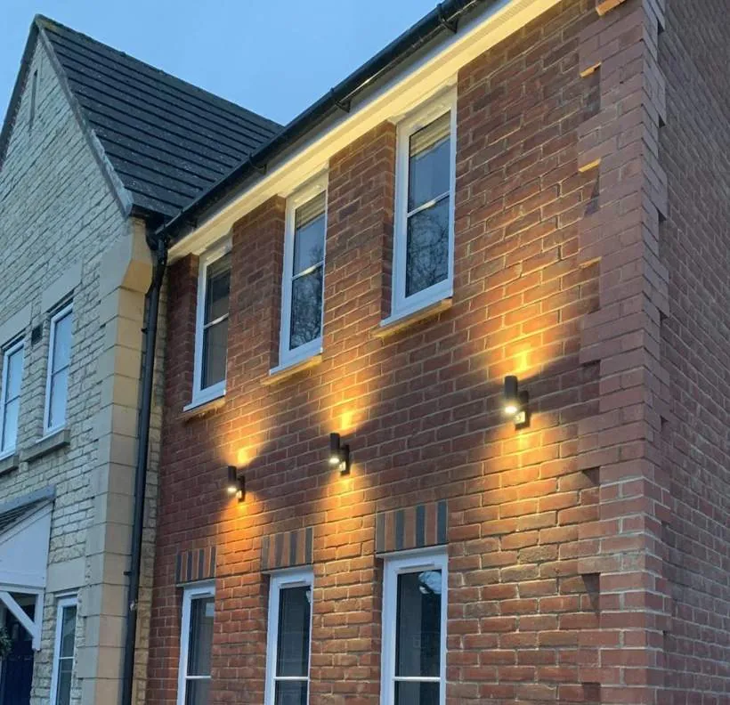 Three high-level up and down wall lights on the brick face of a new two-storey extension, Bicester