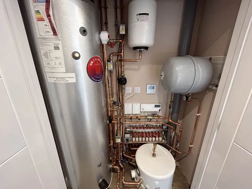 Plant cupboard with a heat pump hot water cylinder, expansion vessels, manifold and neatly wired controls, Marcham near Abingdon