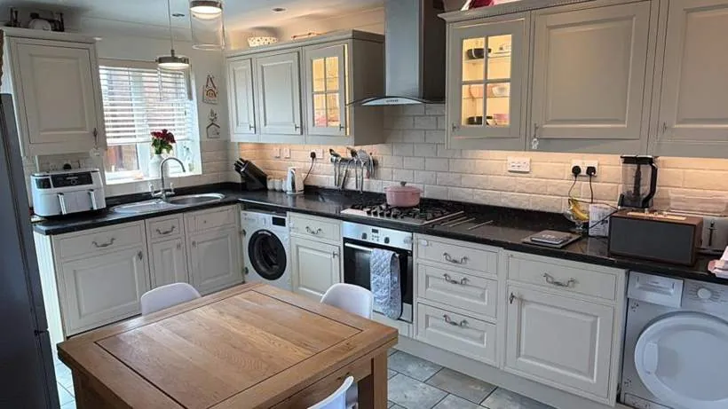 Kitchen with warm LED strip lighting beneath and above the wall cabinets and lit glass-fronted units, Bicester