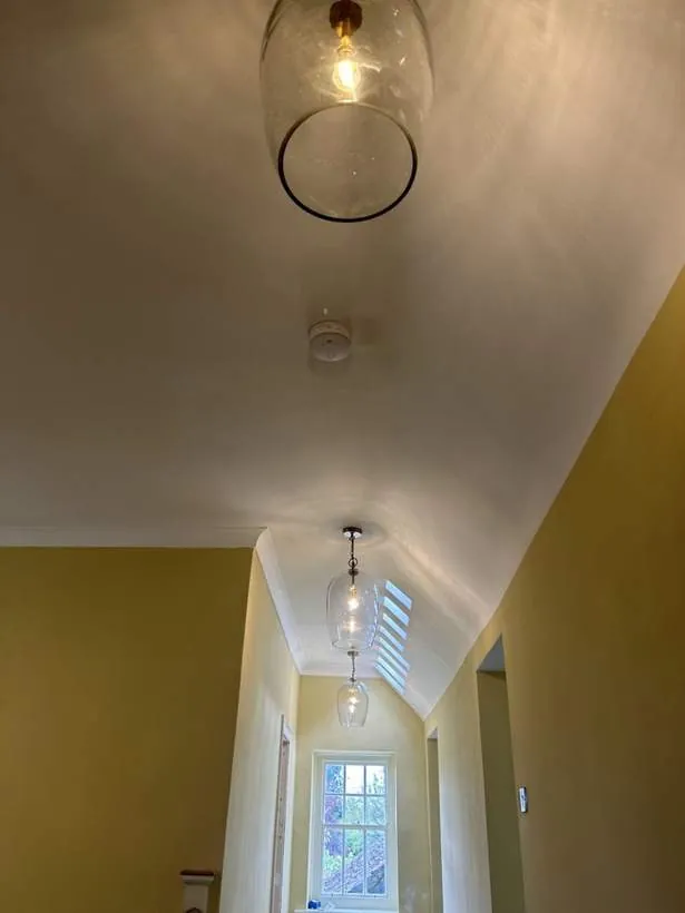 Clear glass bell pendant lights hung in a row along a landing and hallway