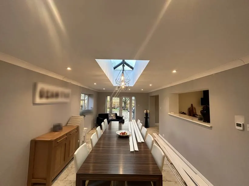 Finished open-plan dining extension with downlights and geometric pendants hanging beneath the roof lantern, Brackley