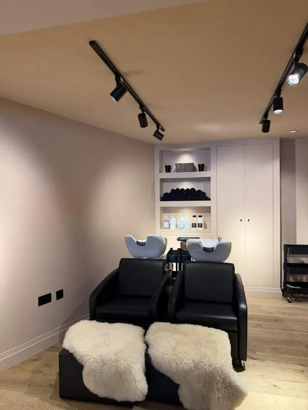 Salon backwash area lit by ceiling track spotlights, with lit display shelving and new sockets, Lechlade