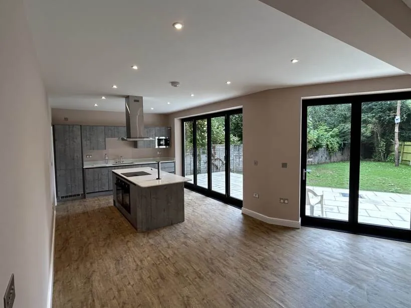 Open-plan kitchen with island, recessed downlights and bifold doors to the garden in a new build home, Marcham near Abingdon