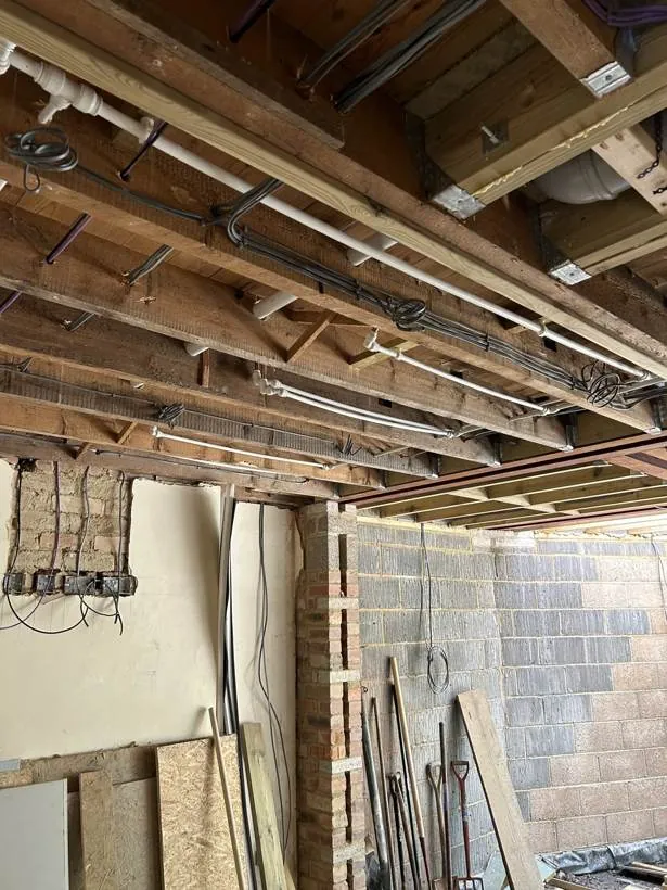 Neatly clipped first fix cable runs through open ceiling joists during a rewire and extension in Oxford