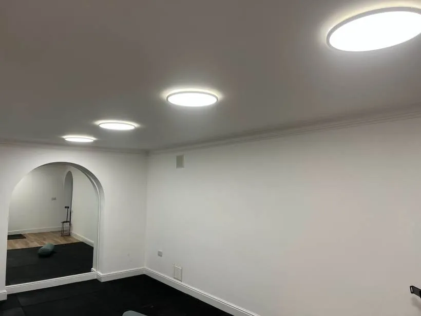 Basement gym lit by flush round LED ceiling lights, with arched openings and rubber flooring, Chinnor