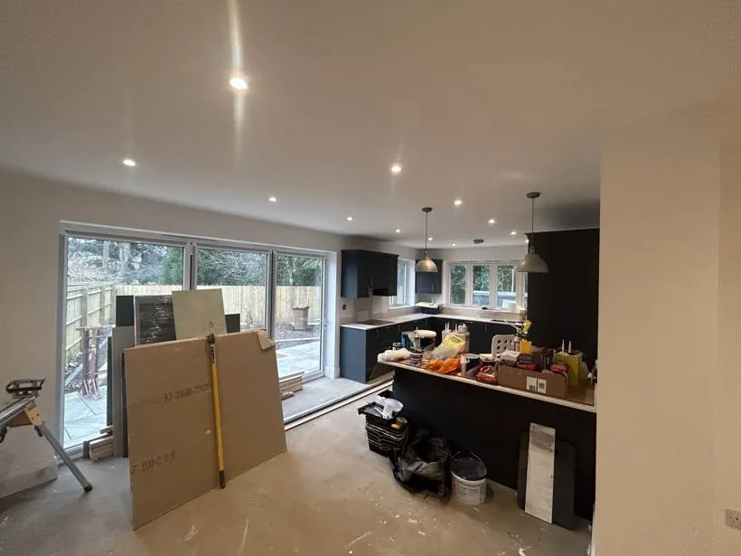 Open-plan kitchen extension with recessed downlights and pendant lights over the island, with decorating materials still on site, Oxford
