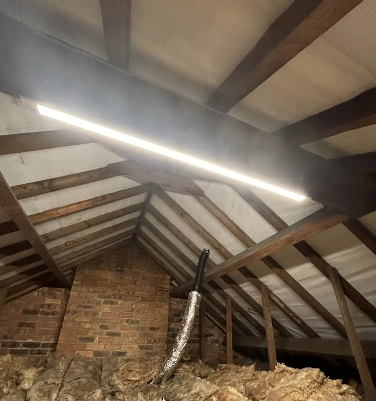 Loft space lit by a new LED batten fixed to the roof timbers, part of a full rewire in Oxford