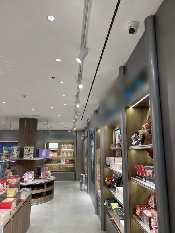 Long retail aisle with downlights, track spotlights and lit display shelving, completed fit-out in Oxford