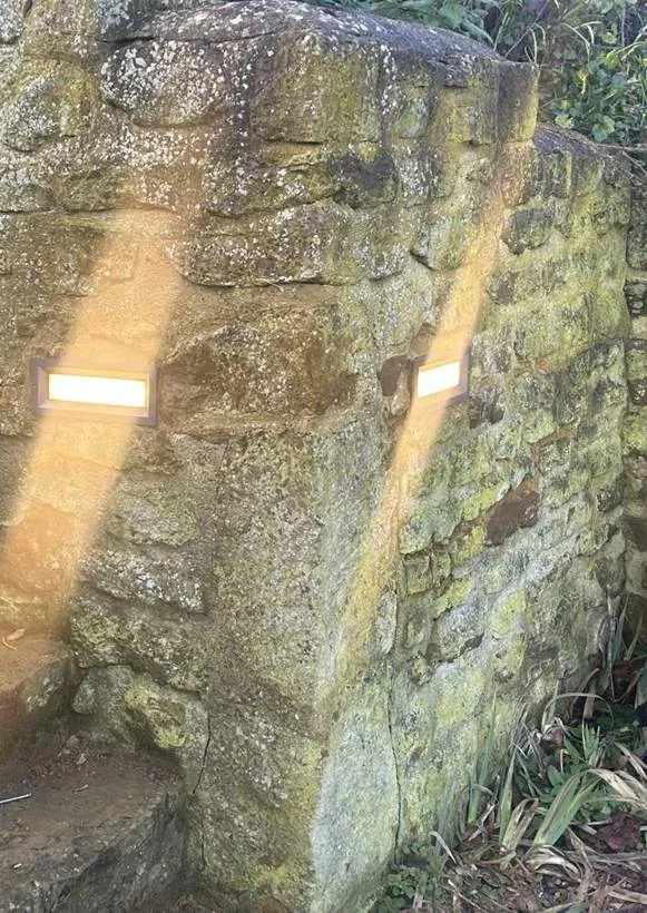 Recessed brick lights set into an old Cotswold stone garden wall beside stone steps, washing light down the wall, Balscote near Banbury