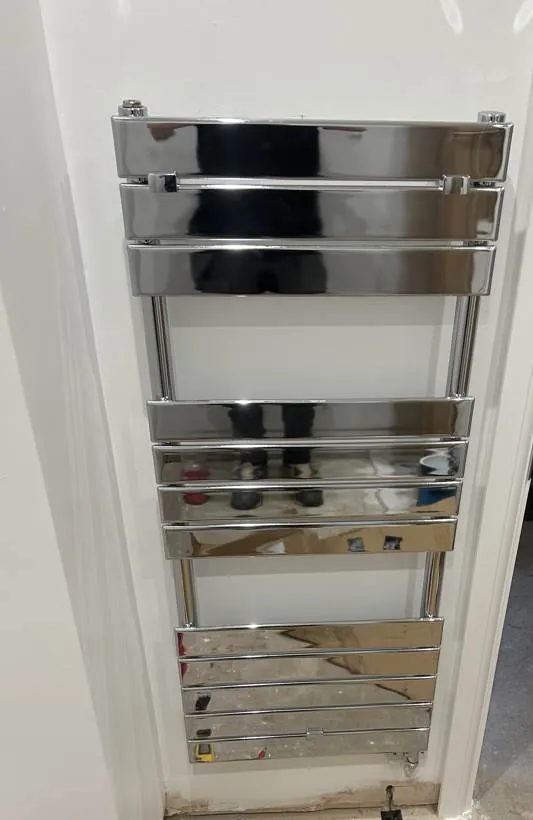 Chrome electric towel rail mounted on a bathroom wall with its supply neatly concealed, Oxford