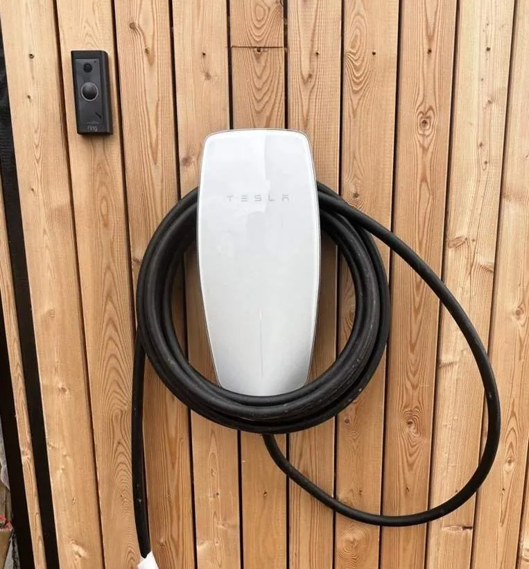 White Tesla Wall Connector on timber cladding of a new build home at Graven Hill, Bicester