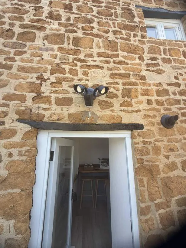 Ring floodlight security camera mounted above a doorway on a stone cottage wall, Hempton, Oxfordshire