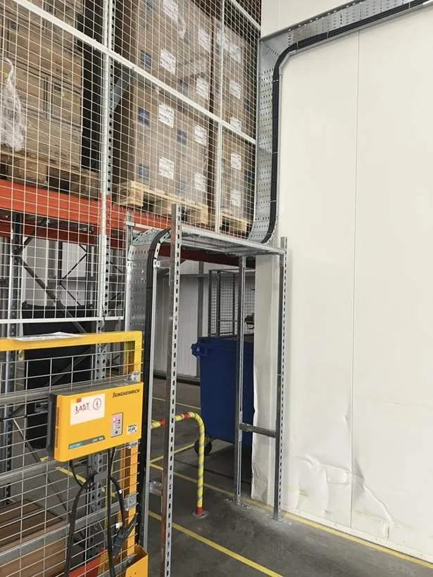 Galvanised cable tray and supports dropping supply cables down to relocated forklift chargers beside warehouse racking, Bicester
