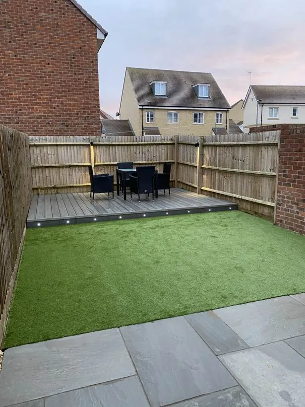 Garden with grey composite decking edged by LED deck lights and spotlights on the fence posts, Milton Keynes