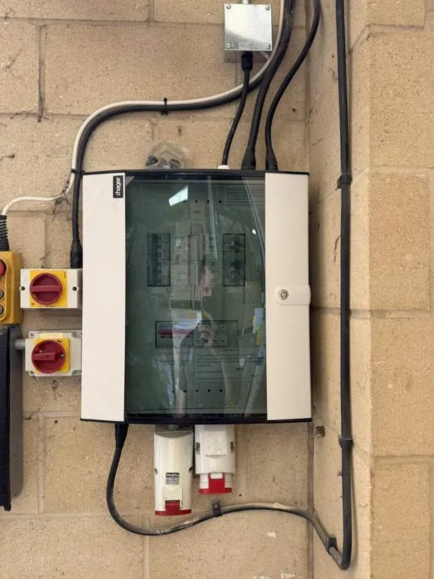 New distribution board on a blockwork wall with rotary isolators and red commercial sockets beneath, Bicester