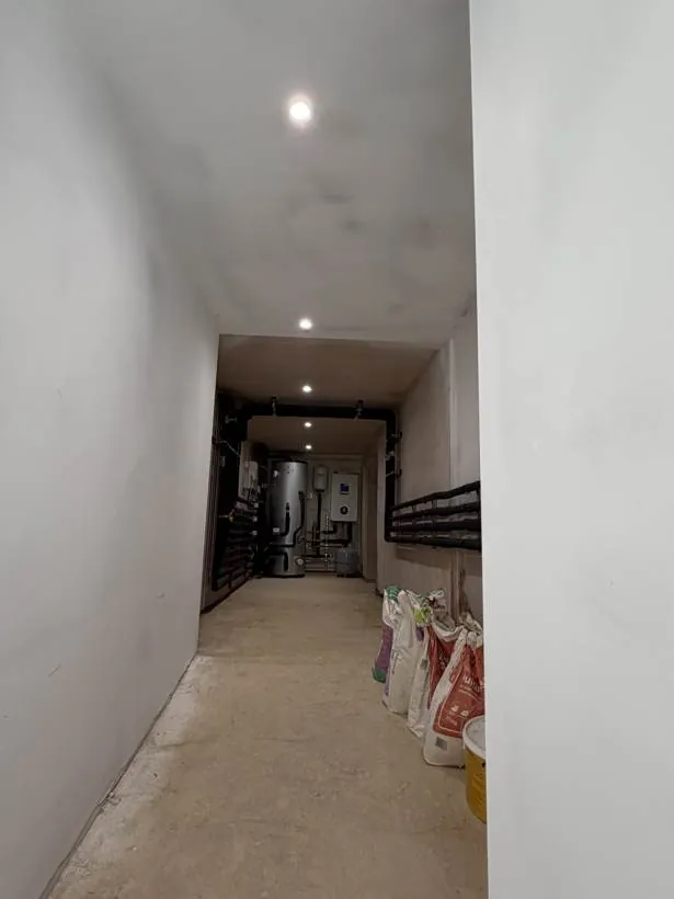 Basement corridor lit by recessed downlights leading to the plant room, during the renovation, Bloxham