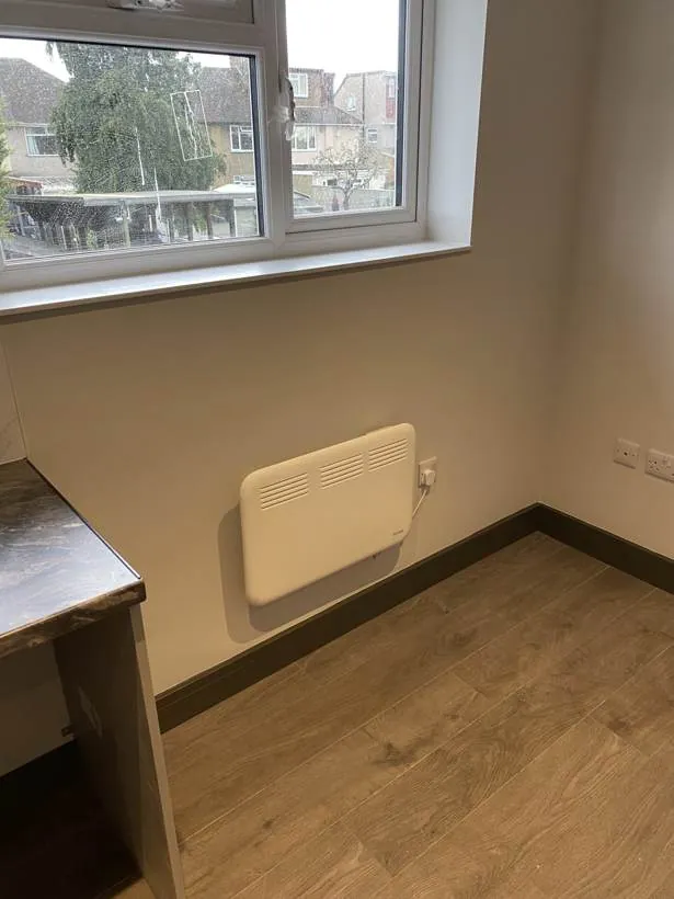 Electric panel heater and double sockets on the wall of a newly finished HMO room, Feltham