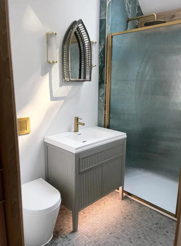 Finished shower room with brass and fluted glass wall lights either side of an arched mirror, village near Bicester