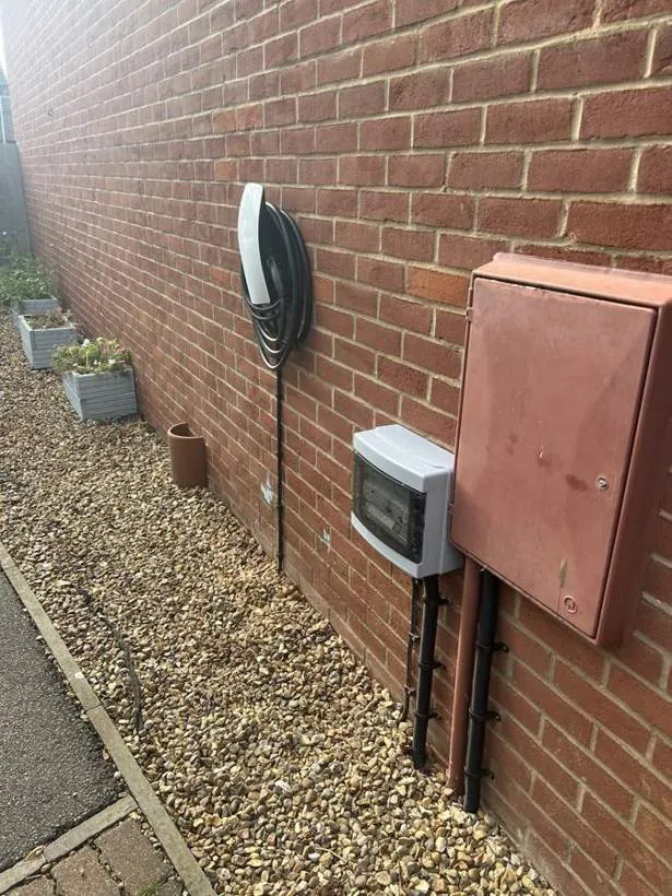 Tesla Wall Connector beside the meter cabinet and isolator on a brick wall, Ambrosden near Bicester