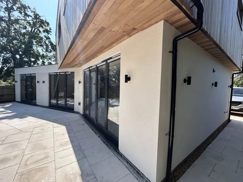 Rendered rear elevation of a new build home with external wall lights and a timber-clad overhang, Marcham near Abingdon